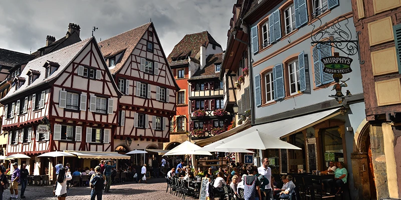 Café terraces beneath half-timbered buildings in Colmar