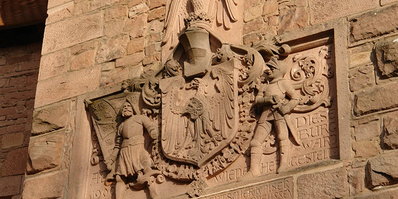 Carved stone coat of arms set into the sandstone wall at Haut-Koenigsbourg
