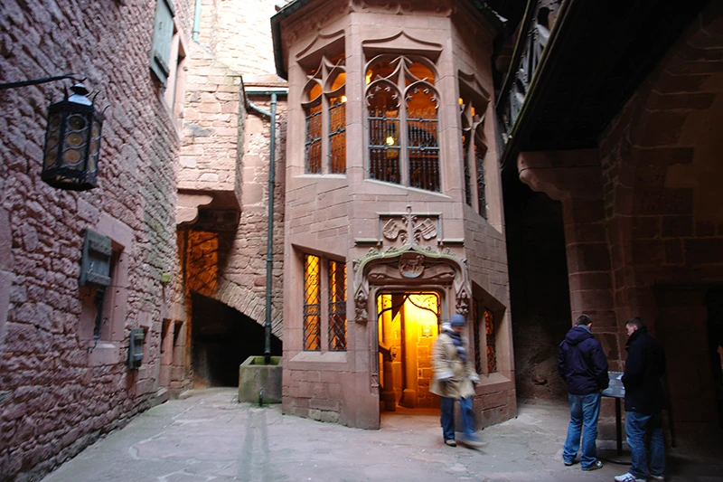 Inner courtyard of Haut-Koenigsbourg with lit windows in the red sandstone