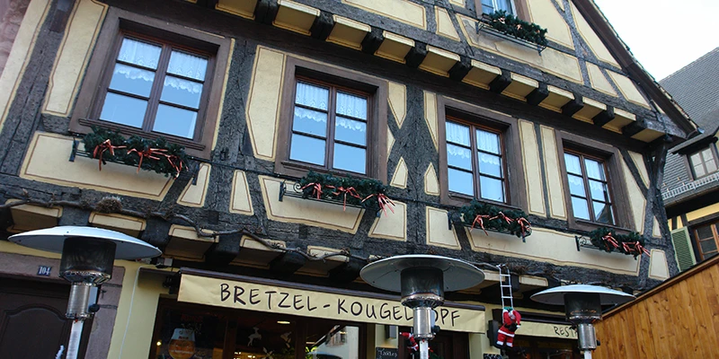 Bakery sign advertising pretzels and kougelhopf on a half-timbered building in Kaysersberg
