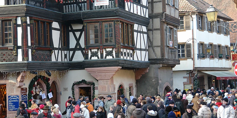 Visitors gathered in front of a half-timbered building at the Kaysersberg Christmas market