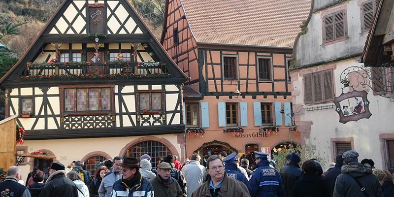 Painted half-timbered building above the Christmas market crowd in Kaysersberg