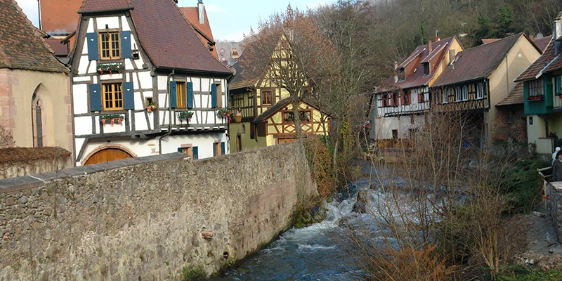 Houses along the Weiss stream in Kaysersberg with the valley beyond