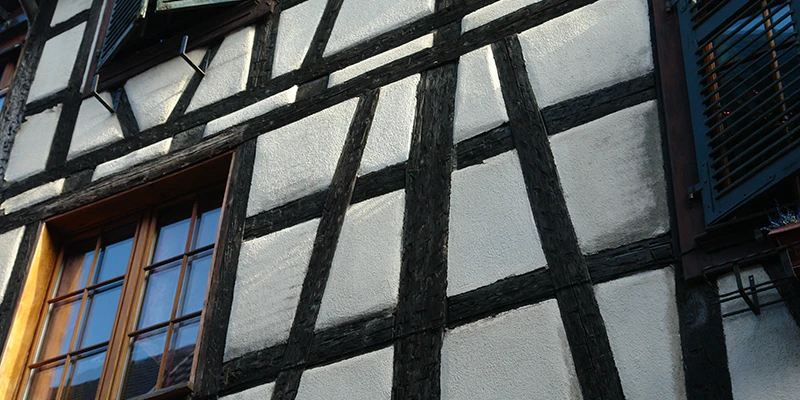 Close view of dark timber framing and a shuttered window in Kaysersberg