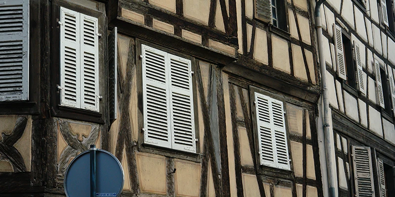 Painted facade with white shutters and timber framing in Kaysersberg