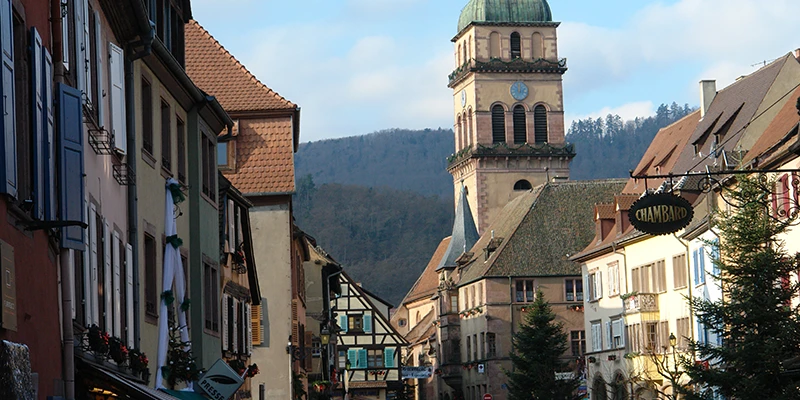 View along the Kaysersberg main street toward the church tower with the Vosges foothills behind