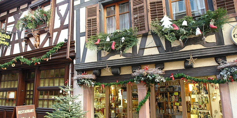 Half-timbered shopfront in Ribeauvillé decorated with fir garlands for Christmas