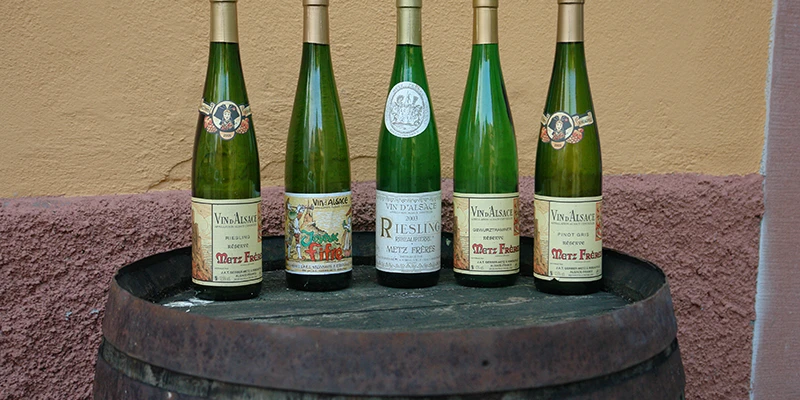 Alsace wine bottles standing on a barrel outside a cellar in Ribeauvillé