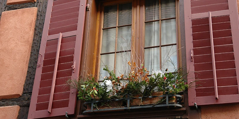 Coral facade with red shutters and window boxes in Ribeauvillé