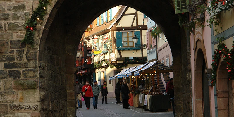 Stone gate arch in Ribeauvillé framing the street and market beyond