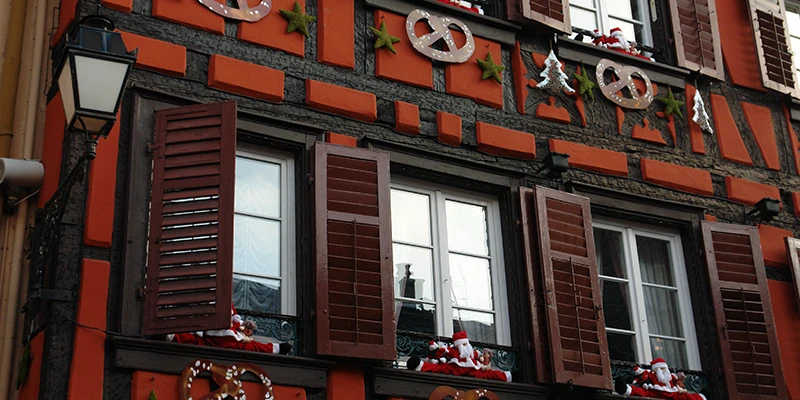 Red half-timbered building in Ribeauvillé hung with wrought-iron pretzel signs
