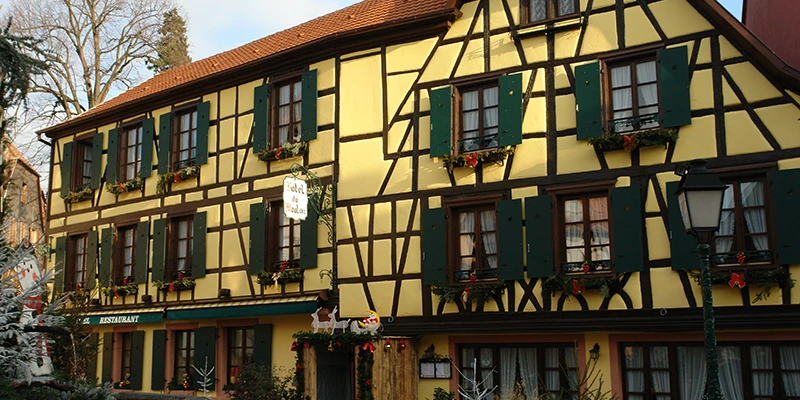 Yellow half-timbered facade with green shutters in Ribeauvillé