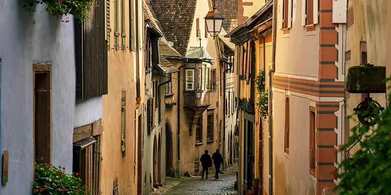 Narrow cobbled lane in Riquewihr with overhanging upper floors