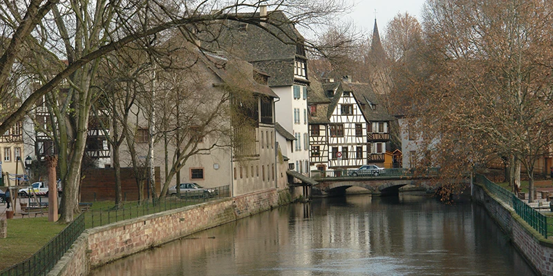 A weir on the River Ill in Strasbourg with bare winter trees along the bank