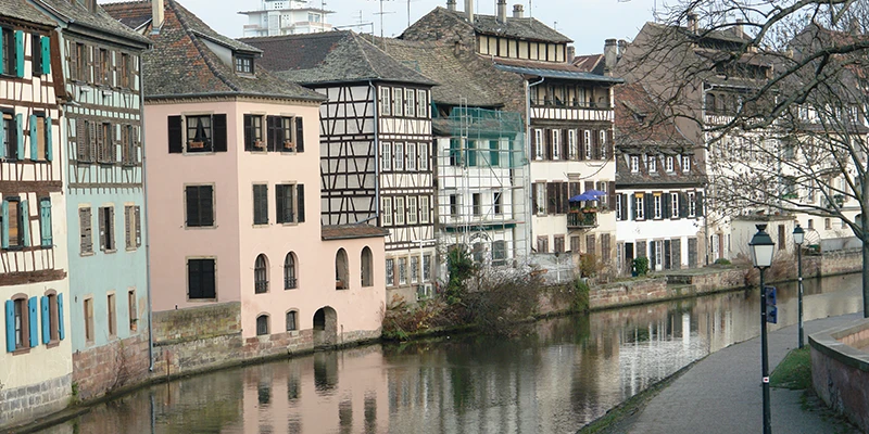 Pastel-painted houses reflected in the still water of a Petite France canal
