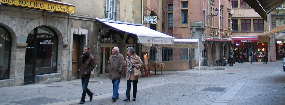 Pedestrians walking beneath awnings on a street in Old Lyon