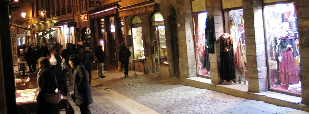 Shops lit at night with people walking in Old Lyon