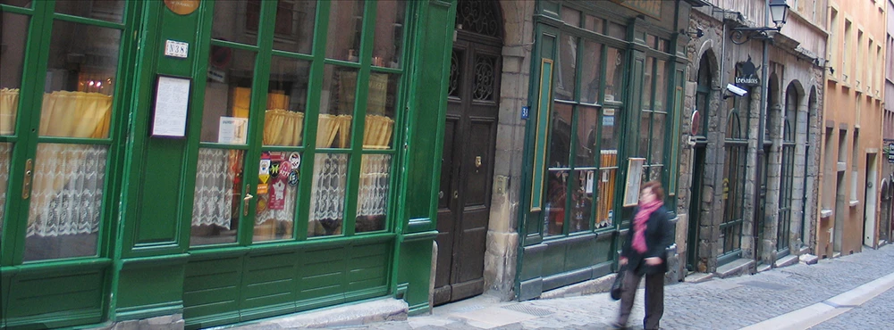 Bright green shopfront and a person walking in Old Lyon