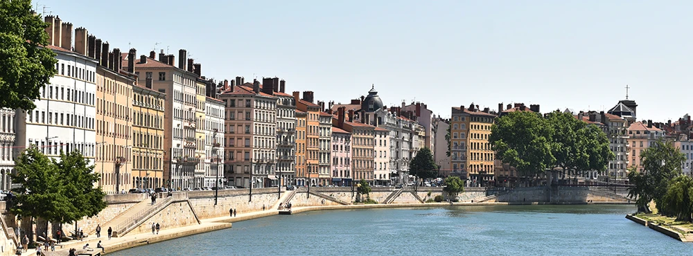 Colorful riverfront buildings along the Saone in Lyon with trees on the bank