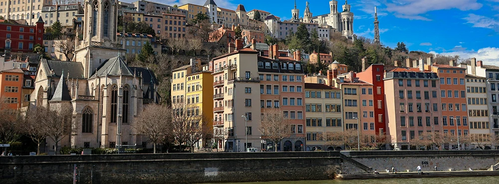 Row of tall buildings along the Saone riverbank in Lyon with arcades below