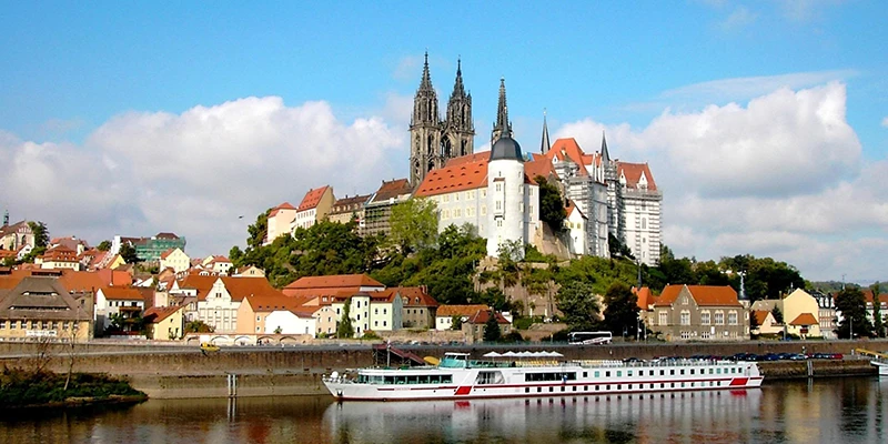 The Albrechtsburg and cathedral above Meissen with a white riverboat on the Elbe