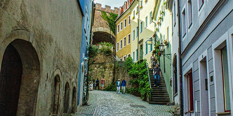 Steep cobbled lane in Meissen with an archway, stairs, flowers and walkers