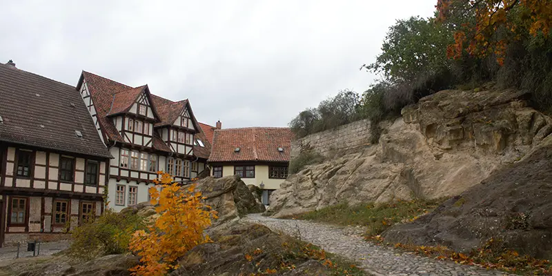 A cobbled path climbing the castle hill between timber houses and sandstone rock