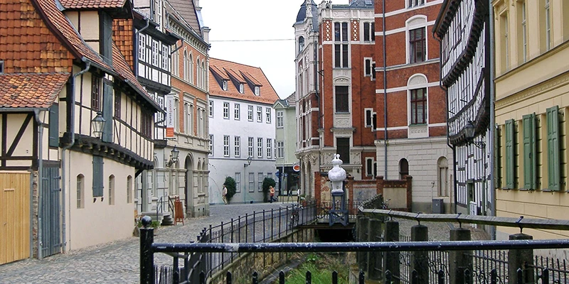 A quiet lane with a small canal, iron railings and a bridge among old houses