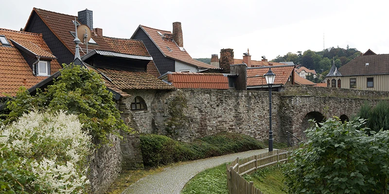 Cobbled path running below Wernigerode's old town wall, with gardens, a lamp post and rooftops above