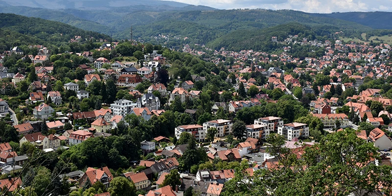 Panorama over Wernigerode's red rooftops toward the wooded Harz hills and the distant Brocken summit