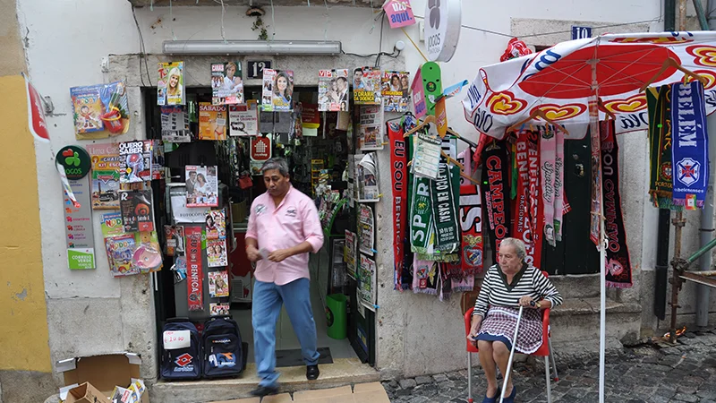 Small Alfama shop with goods hanging outside under an umbrella