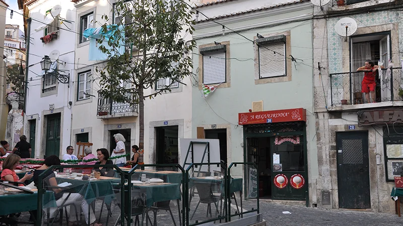 Outdoor restaurant tables set out in a narrow Alfama lane