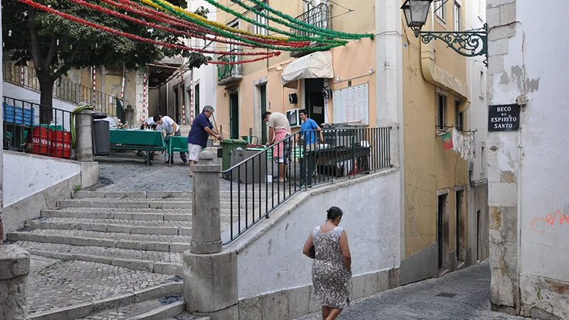 Narrow lane in the Alfama district with a man walking beneath overhanging greenery