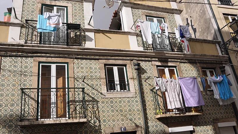 Tiled building facade in Alfama with laundry hanging from the windows