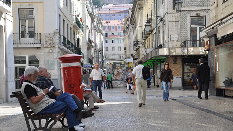 Pedestrian street in the Baixa with a red mailbox and a man on a bench