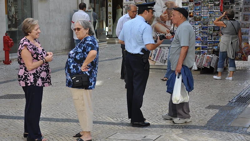 Group of older residents standing and talking on a Lisbon street