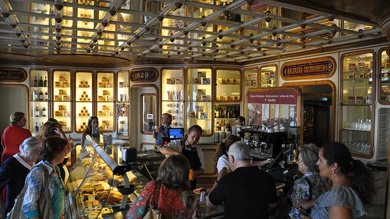 Ornate old cafe and pastry shop interior busy with customers in Lisbon