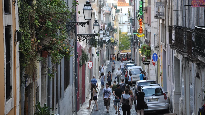 Bairro Alto street dropping steeply downhill past parked cars