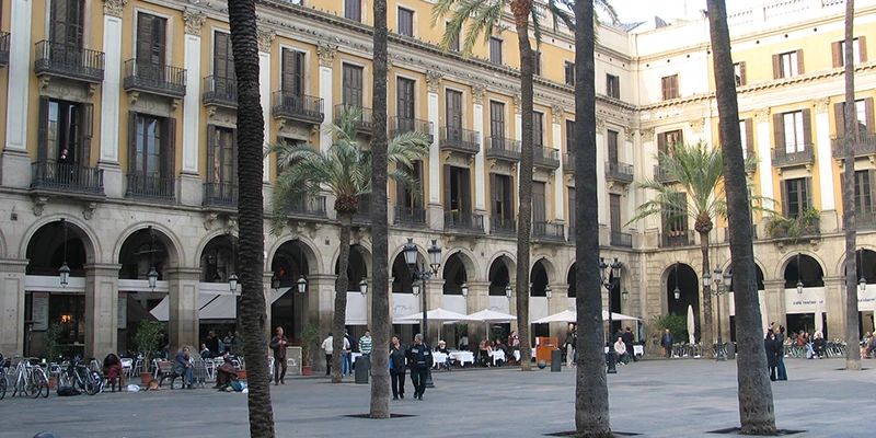 Plaça Reial at dusk with palm trees, lampposts and busy outdoor cafes