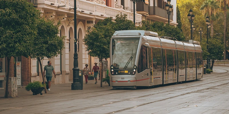 Modern tram on a broad avenue in Seville passing classic architecture