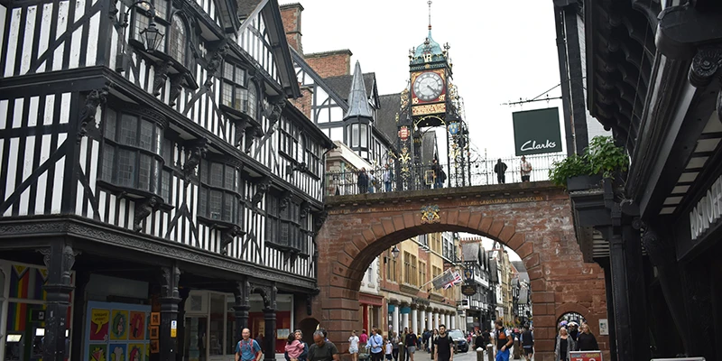 Red sandstone gate arch in Chester framed by half-timbered buildings