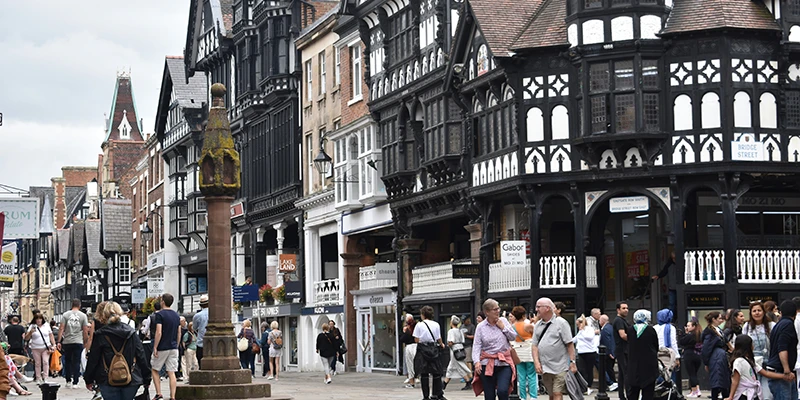 Busy pedestrian street corner in central Chester with timbered facades