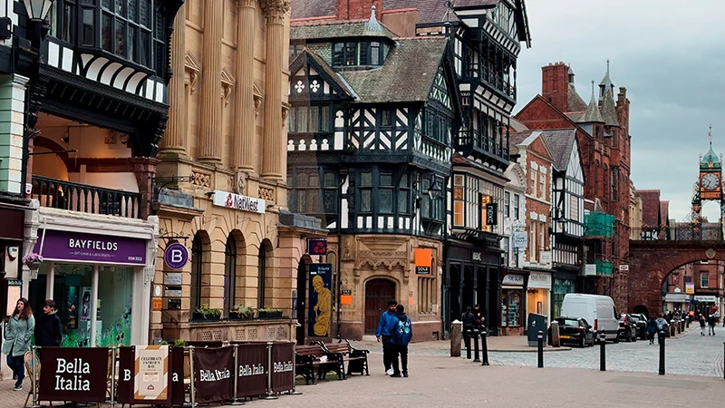 Timbered buildings in Chester with red sandstone stonework behind