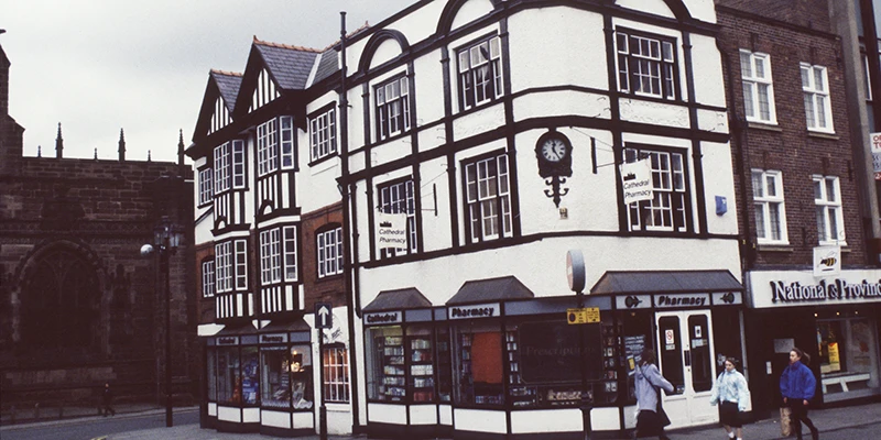 Large black-and-white timbered building beside a brick wall in Chester