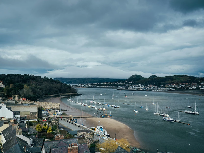 The Conwy estuary with moored boats and the harbor below the town