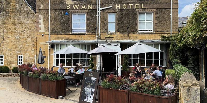 The Swan Hotel facade with diners at outdoor tables under white umbrellas