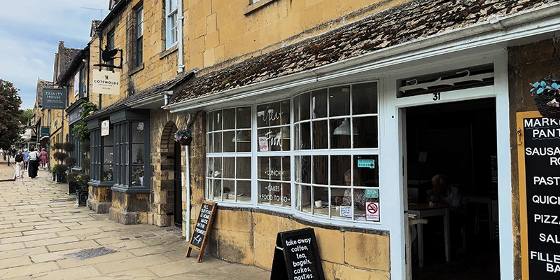 Cotswold Pantry cafe with bow window and sandwich-board signs advertising lunch, cakes and pastries