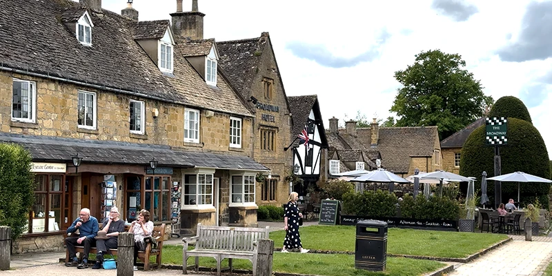 People sitting on a bench eating ice cream alongside the village green