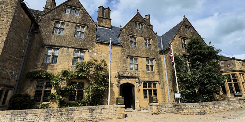 The grand Tudor-style stone facade of The Lygon Arms hotel with gabled rooflines and entrance porch