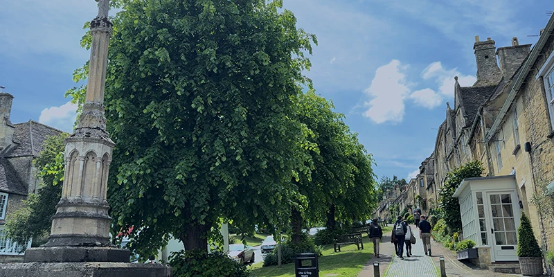 War memorial cross and church area with stone cottages and tree-lined path